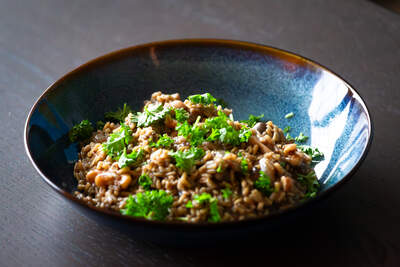 Cremet havrerisotto med champignon, hvidløg og timian; gyldne korn, svampe og frisk persille giver appetit.