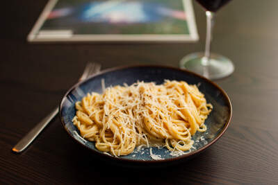 Cremet carbonarasauce, toppet med revet parmesan og sorte peberkorn på en blå tallerken