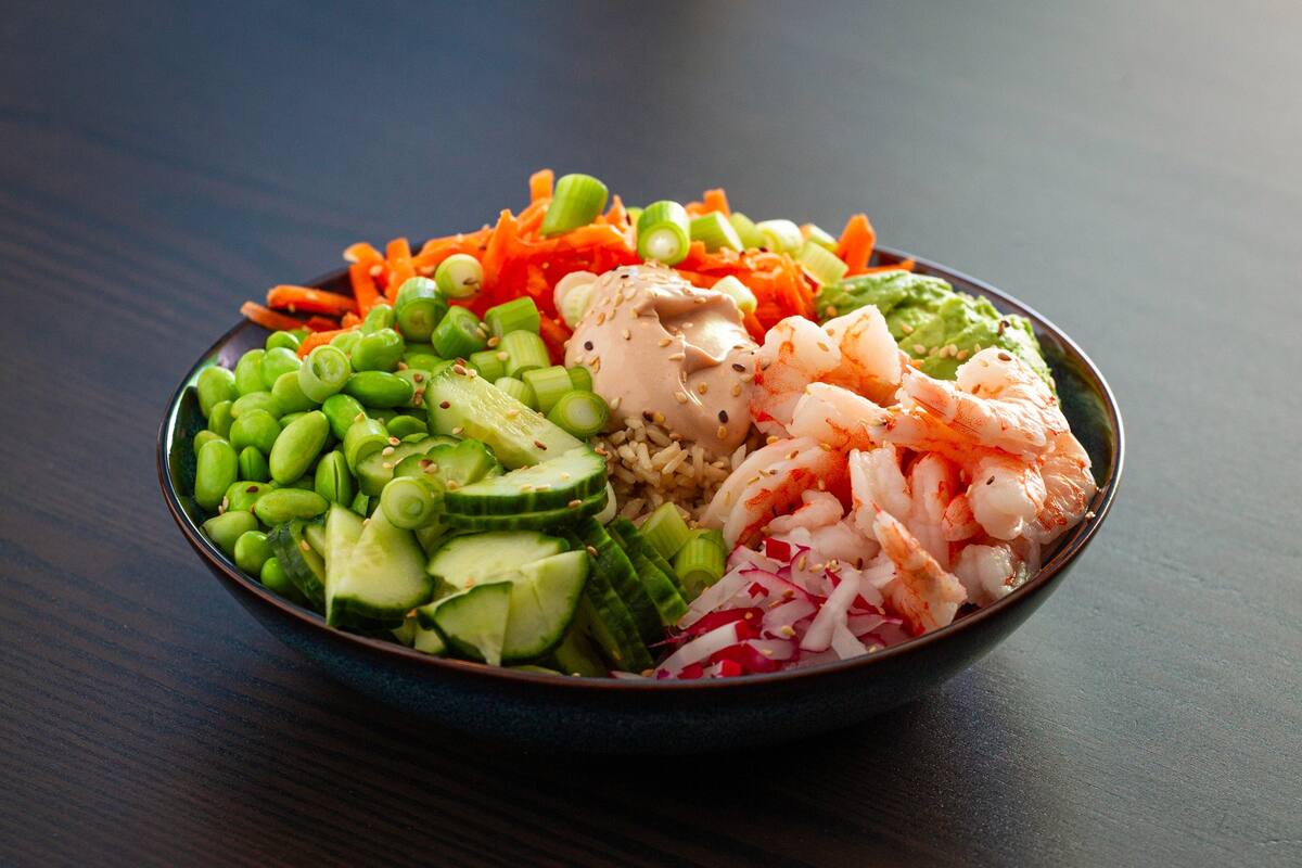 Pokebowl med tigerrejer, agurkeskiver, forårsløg, gulerod, ris og sesamfrø med cremet sesamdressing.