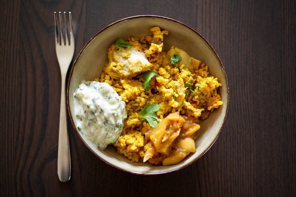 Gylden biryani med kylling, orange ris, koriander og cremet yoghurtdip.