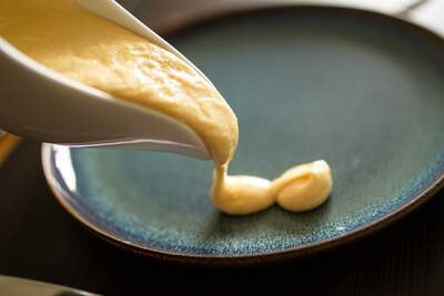 Hollandaise sauce hældes på tallerken