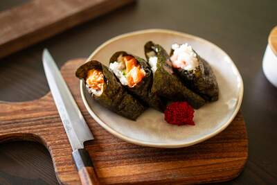 Fire onigiri indpakket i nori-tang med spicy tun og sesamris på en tallerken
