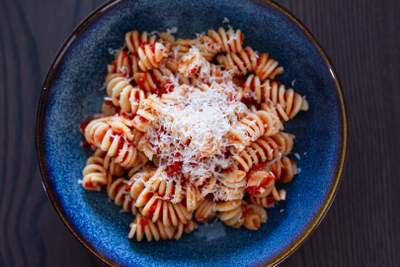 Al dente fusilli i krydret rød tomatsauce med friskrevet ost på blå tallerken.