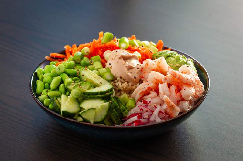 Pokebowl med tigerrejer, agurkeskiver, forårsløg, gulerod, ris og sesamfrø med cremet sesamdressing.