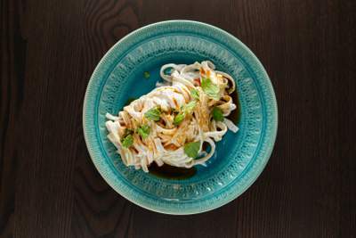 Turkis blå skål med tyrkisk pastaret i cremet yoghurt-smør sauce toppet med mynte og paprika.