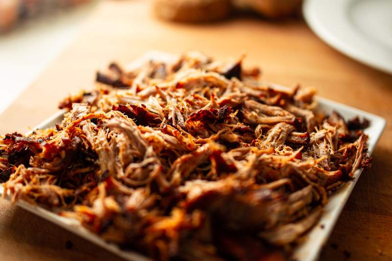 Pulled pork i ovn, saftigt og møre strimler med gyldne, sprøde kanter på tallerkenen.